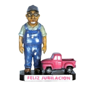 Figura de jubilado con mono azul y gafas, vista frontal, junto a camioneta rosa con base 'Feliz Jubilación