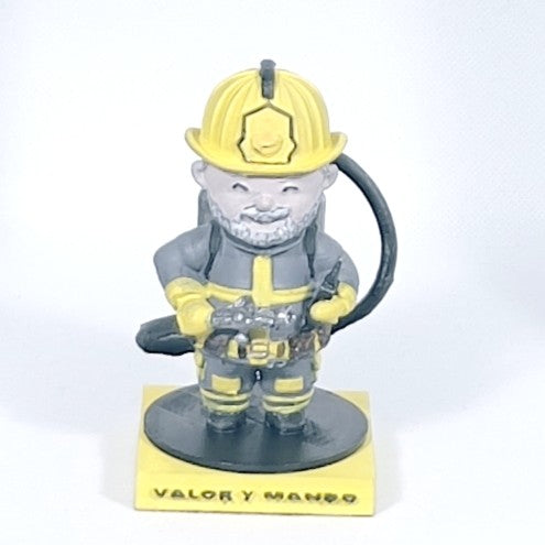 Figura 3D de bombero con manguera vista frontal, casco amarillo, barba gris y base con texto Valor y Mando
